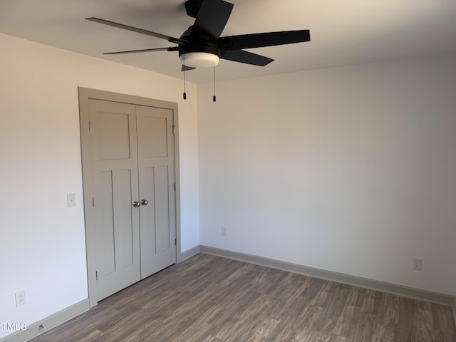 unfurnished bedroom with a ceiling fan, a closet, baseboards, and wood finished floors