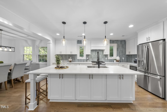 kitchen featuring light countertops, stainless steel fridge, backsplash, and white cabinetry