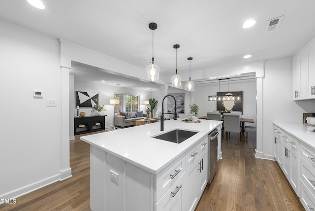 kitchen with dark wood-style floors, hanging light fixtures, stainless steel dishwasher, white cabinets, and a sink