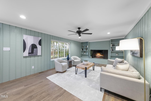 living area featuring recessed lighting, visible vents, a ceiling fan, a brick fireplace, and wood finished floors