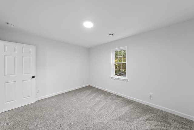 carpeted spare room with visible vents and baseboards