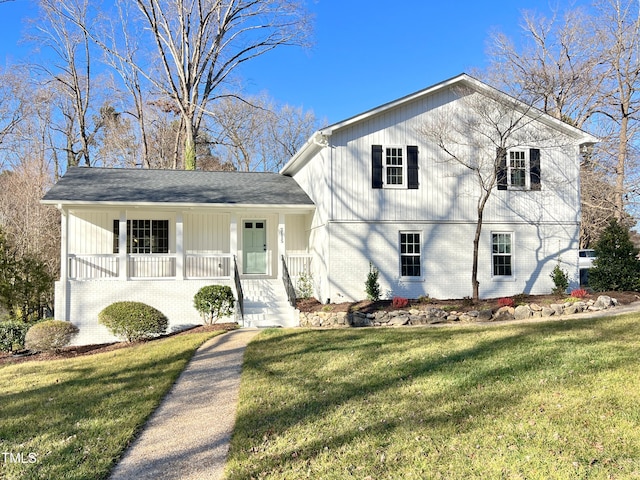 split level home featuring a front yard, covered porch, and brick siding