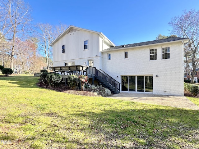 back of property featuring brick siding, a yard, stairway, a wooden deck, and a patio area