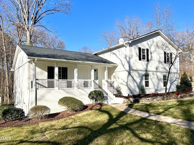 split level home with covered porch, a chimney, a front lawn, and brick siding