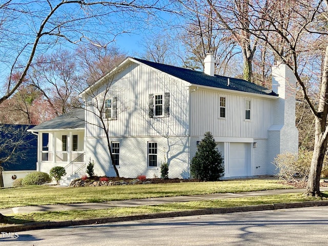 view of front facade with an attached garage, brick siding, a chimney, and a front yard