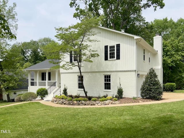 view of front of property featuring a front lawn, brick siding, and a chimney