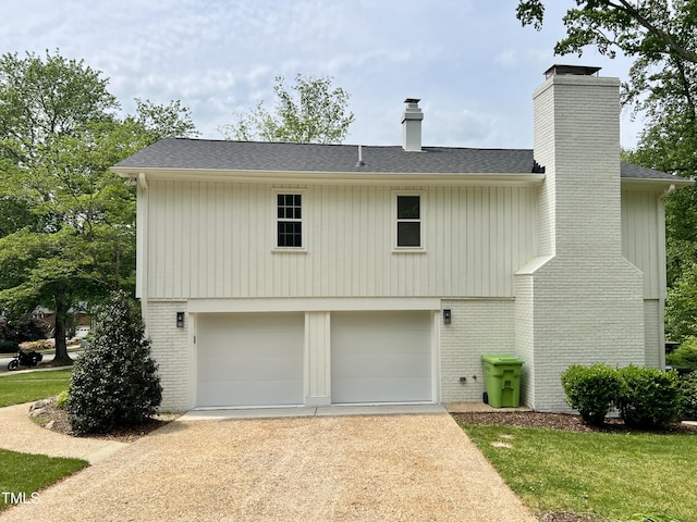 exterior space featuring brick siding, driveway, a chimney, and a garage