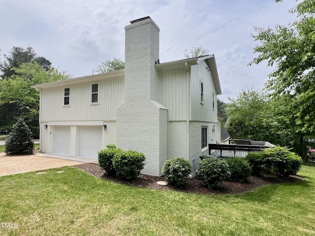 rear view of property featuring brick siding, a yard, an attached garage, and a chimney