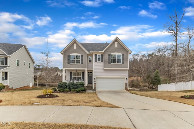 traditional home featuring driveway, stone siding, an attached garage, fence, and a porch