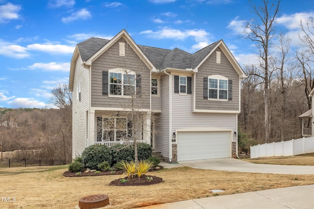 traditional home with a garage, stone siding, fence, and concrete driveway