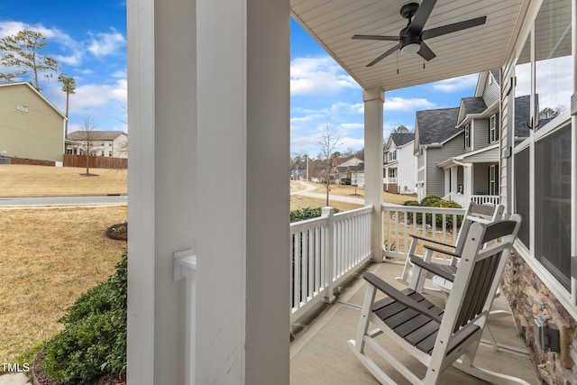 balcony featuring covered porch, ceiling fan, and a residential view