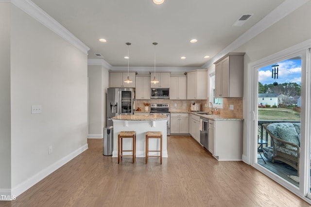 kitchen featuring stainless steel appliances, decorative backsplash, light wood-style floors, a sink, and a kitchen breakfast bar