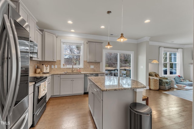 kitchen featuring stainless steel appliances, backsplash, light wood-style flooring, and crown molding