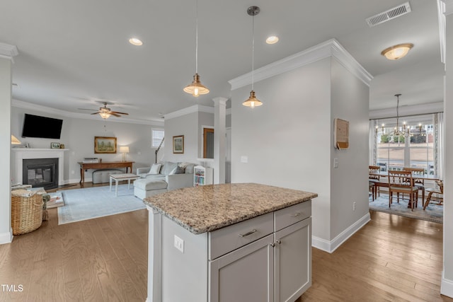 kitchen with ornamental molding, light wood-type flooring, and visible vents