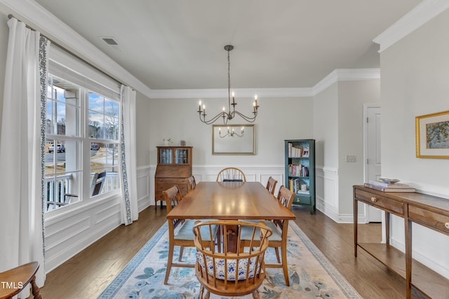 dining space featuring an inviting chandelier, crown molding, visible vents, and hardwood / wood-style floors