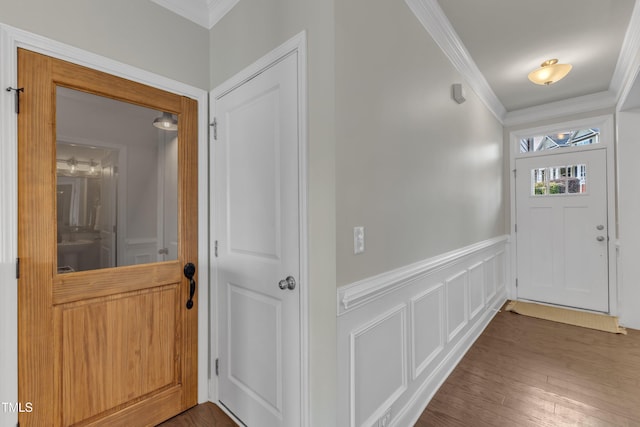 interior space featuring ornamental molding, wainscoting, hardwood / wood-style floors, and a decorative wall