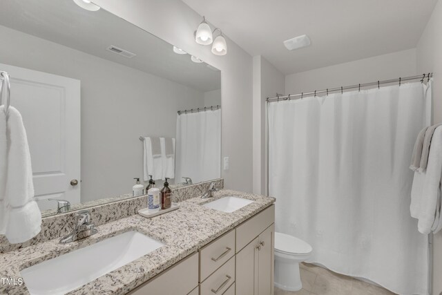 full bathroom featuring visible vents, a sink, toilet, and double vanity