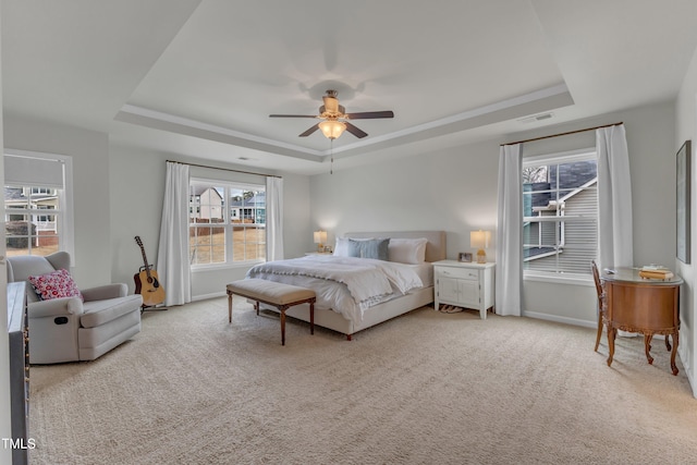 bedroom featuring carpet floors, a tray ceiling, visible vents, and baseboards