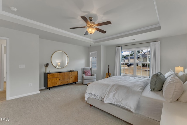 carpeted bedroom with a ceiling fan, baseboards, a tray ceiling, and crown molding