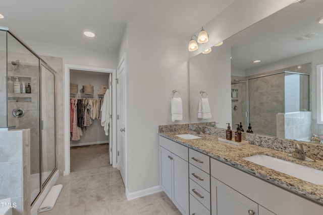 bathroom with double vanity, a shower stall, and a sink