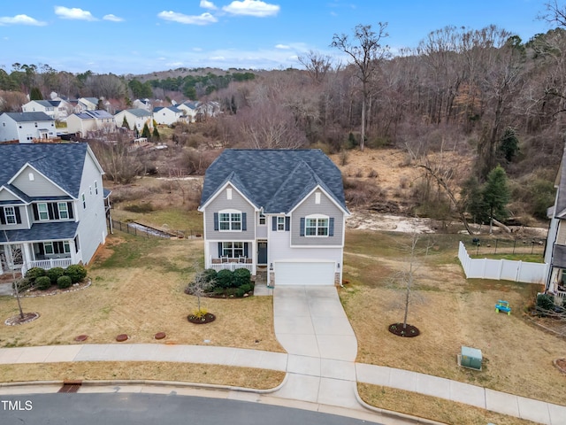 view of front of property featuring a garage, a shingled roof, concrete driveway, fence, and a front lawn