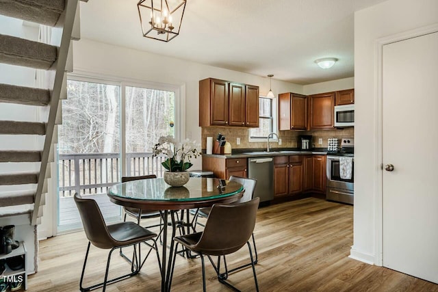 kitchen featuring decorative backsplash, dark countertops, light wood-style flooring, stainless steel appliances, and pendant lighting