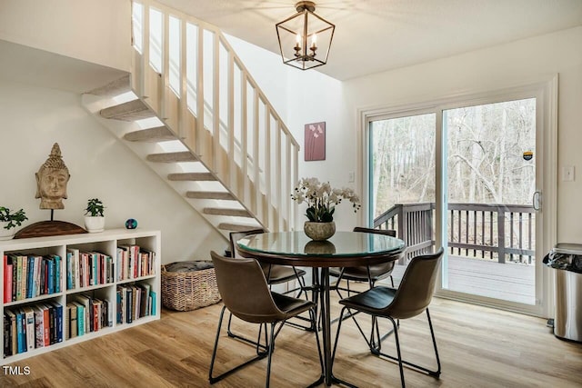 dining space with a notable chandelier, stairway, and wood finished floors