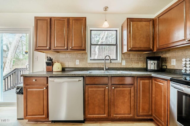 kitchen with stainless steel appliances, dark countertops, brown cabinets, and a sink