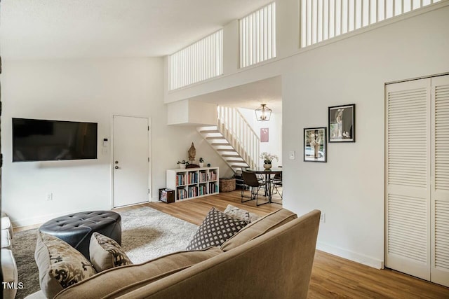 living room with baseboards, a high ceiling, stairway, and wood finished floors