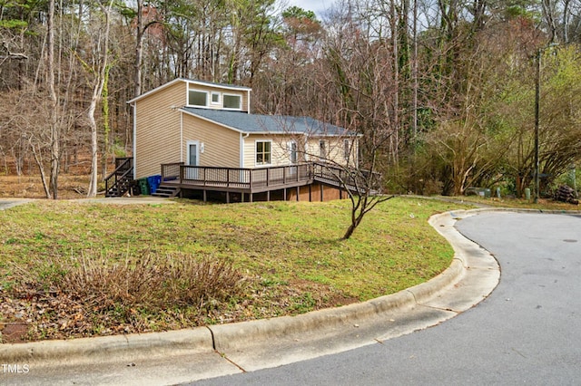 view of front of house with a front lawn, a forest view, and a wooden deck