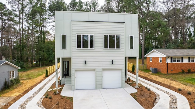 contemporary house with driveway, an attached garage, and central air condition unit