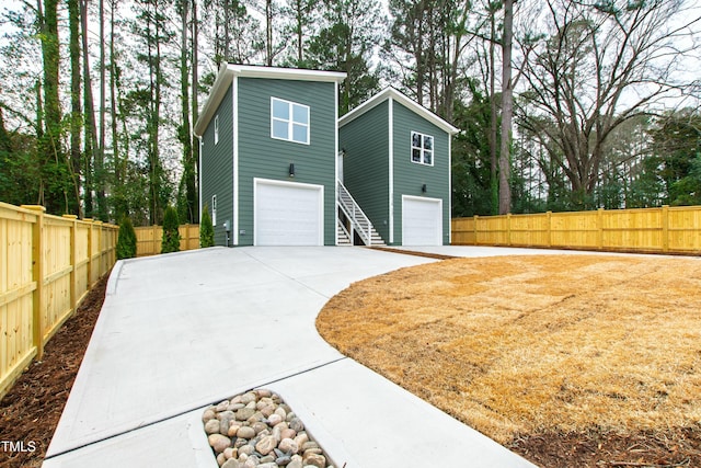 view of front of home with a garage, concrete driveway, and fence