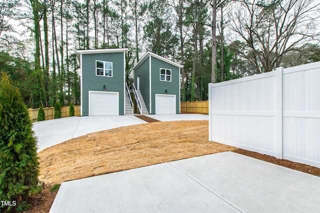 garage with concrete driveway and fence