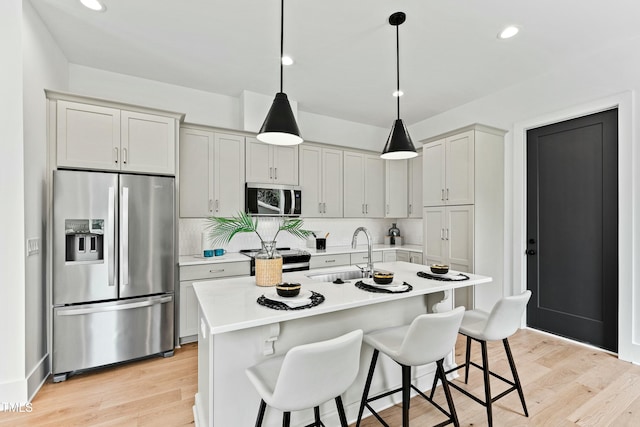 kitchen with stainless steel appliances, a kitchen bar, a sink, and light countertops