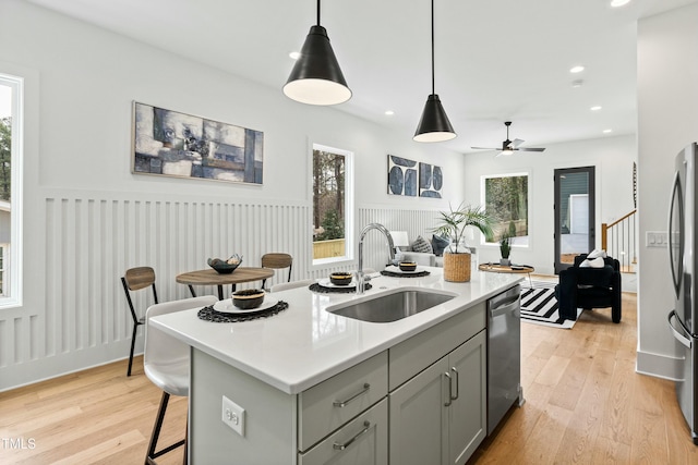 kitchen featuring appliances with stainless steel finishes, light countertops, gray cabinetry, light wood-style floors, and a sink