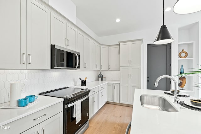 kitchen featuring light countertops, stainless steel microwave, a sink, and electric range