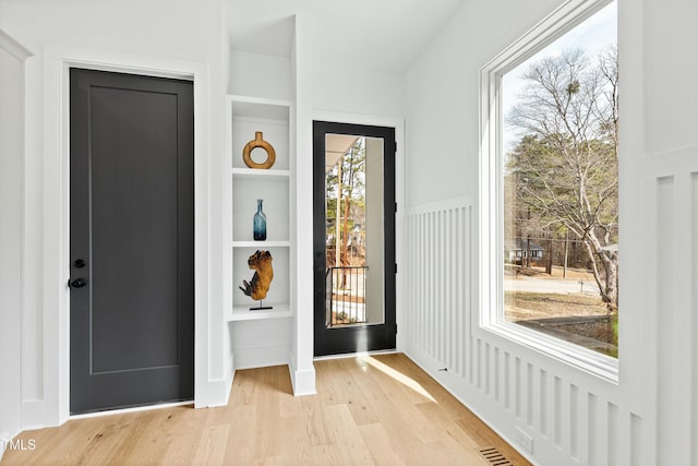 doorway featuring light wood-type flooring and built in shelves