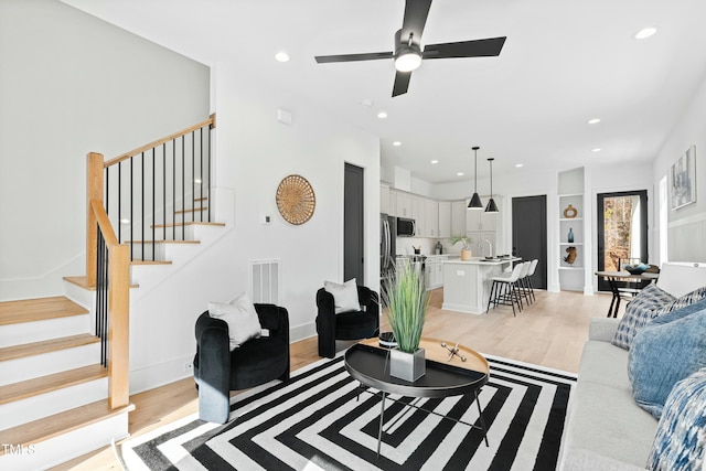 living area featuring recessed lighting, visible vents, baseboards, stairs, and light wood-type flooring