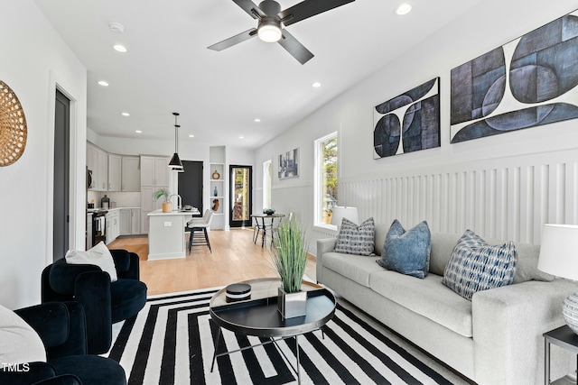 living area with light wood-style floors, a ceiling fan, and recessed lighting