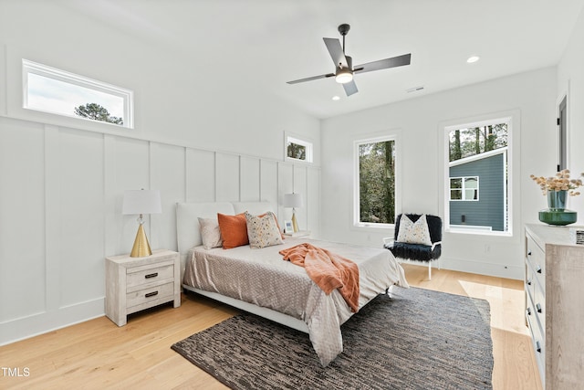 bedroom with light wood-type flooring, ceiling fan, a decorative wall, and recessed lighting