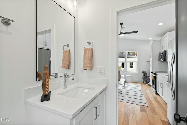 bathroom with recessed lighting, ceiling fan, vanity, and wood finished floors