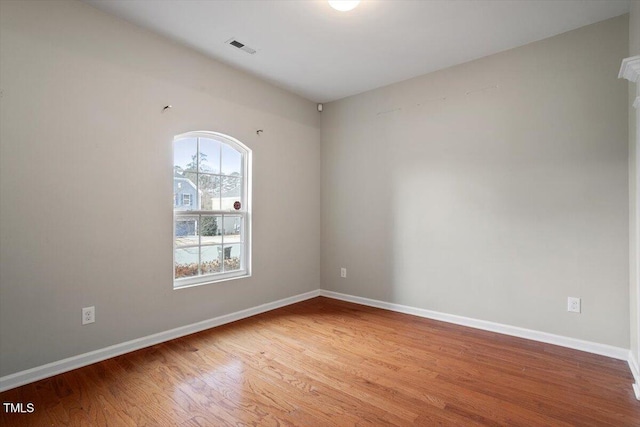 empty room with baseboards, visible vents, and wood finished floors