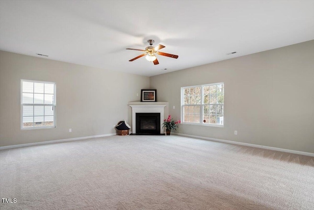 unfurnished living room featuring visible vents, baseboards, a fireplace with flush hearth, ceiling fan, and carpet flooring