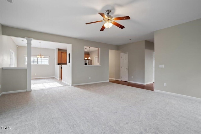 unfurnished living room featuring ceiling fan with notable chandelier, light carpet, and baseboards