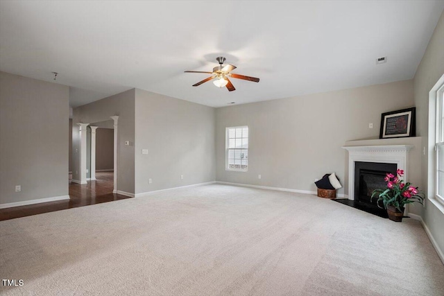 carpeted living area featuring baseboards, a fireplace with flush hearth, visible vents, and a ceiling fan