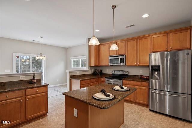 kitchen featuring visible vents, appliances with stainless steel finishes, brown cabinetry, and pendant lighting