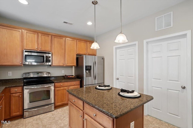 kitchen featuring stainless steel appliances, dark stone countertops, visible vents, and a center island