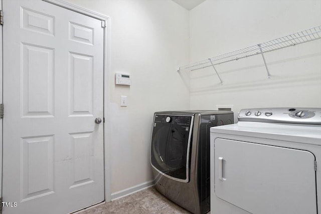 washroom featuring laundry area, washer and clothes dryer, and baseboards