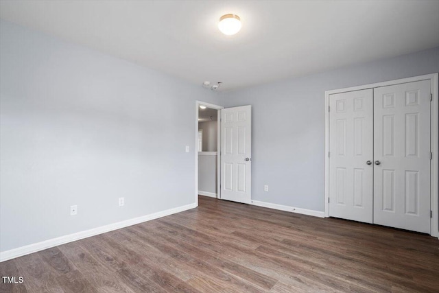 unfurnished bedroom with a closet, baseboards, and wood finished floors