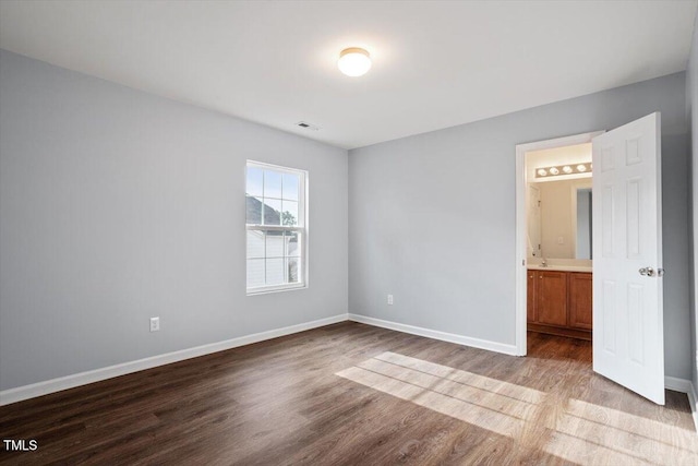 unfurnished room featuring visible vents, baseboards, and wood finished floors